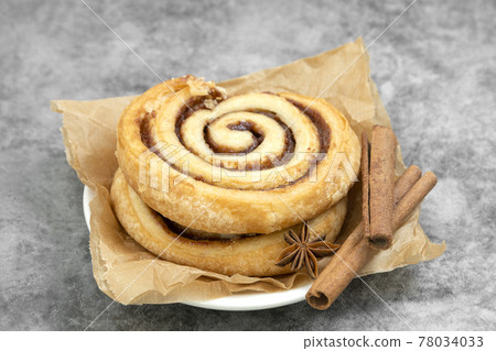 Cinnamon roll with cinnamon sticks over wooden table, danish pastry, sweet pastry for breakfast or snack. 78034033