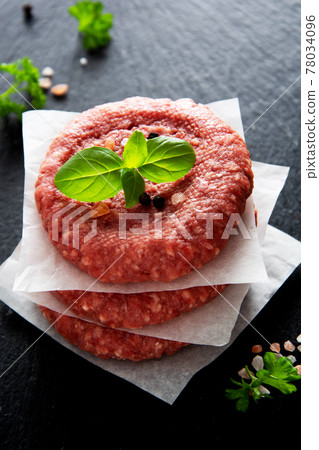 Raw red meat cotlets, cooking burgers. Minced red meat on black board. 78034096