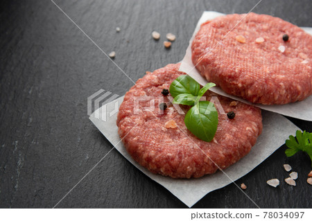 Raw red meat cotlets, cooking burgers. Minced red meat on black board. Copy space 78034097