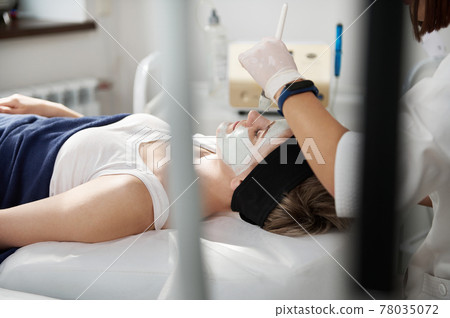 Aesthetician beautician applying an alginic mask on a beautiful woman face at spa clinic. Professional skin care concept 78035072