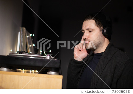 Young unshaven handsome millennial guy focused on music with headphones Young unshaven handsome millennial guy focused on music with headphones 78036028