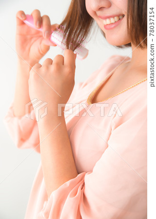 一個年輕女子用刷子梳理頭髮 78037154