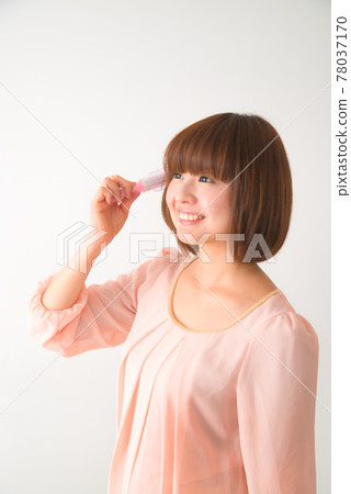 一個年輕女子用刷子梳理頭髮 78037170