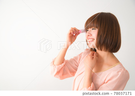 一個年輕女子用刷子梳理頭髮 78037171