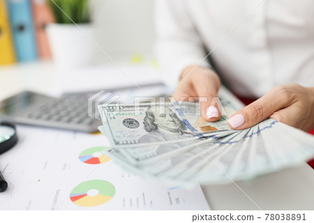 In female hands one hundred dollar bills on table are commercial and financial figures in charts 78038891