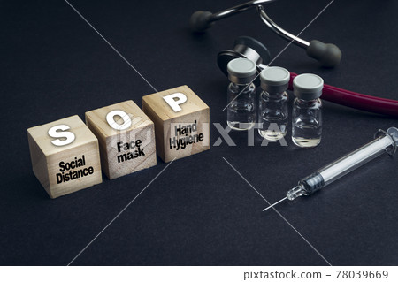 SOP text or Standard Operating Procedure on wooden cube with stethescope and syringe on black background 78039669