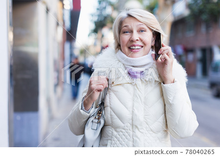 Mature female talking on mobile phone outdoor Mature female talking on mobile phone outdoor 78040265
