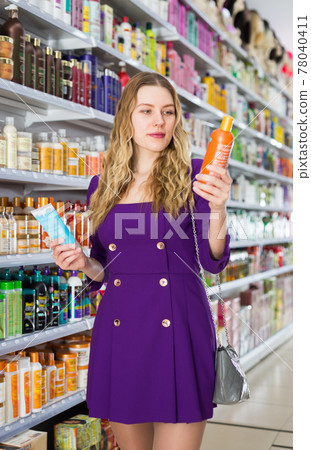 shopper choosing shampoo and balm 78040411