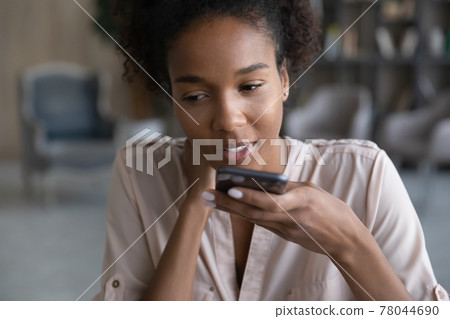 Young african woman dictating audio message on cellphone. 78044690
