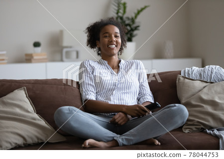 Happy african american woman watching funny smart TV programs. 78044753