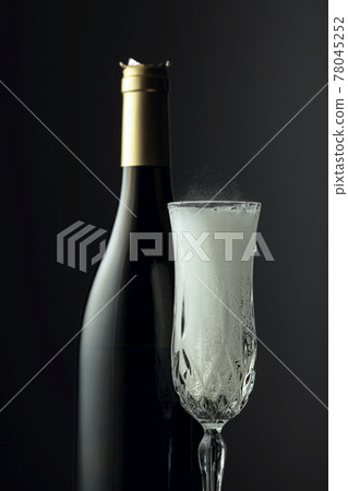Bottle and glass of champagne on a black background. 78045252