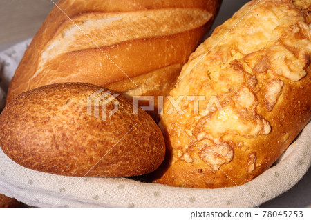 Fresh bread in a basket on a table with a fried crust. 78045253