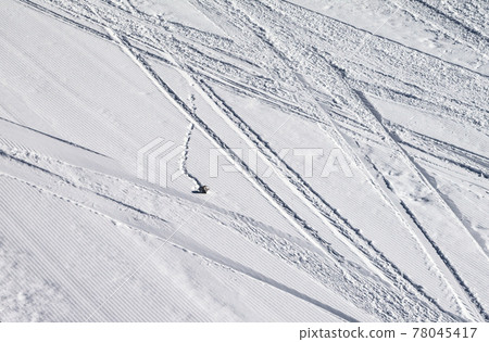 Groomed snowy ski slope with trace from skis, snowboards and stone at winter Groomed snowy ski slope with trace from skis, snowboards and stone at winter 78045417