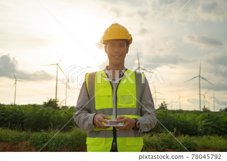Portrait of Asian windmill engineer man, worker working, holding a model on site at wind turbines field or farm, clean energy source. Eco technology for electric. industry nature environment. People 78045792