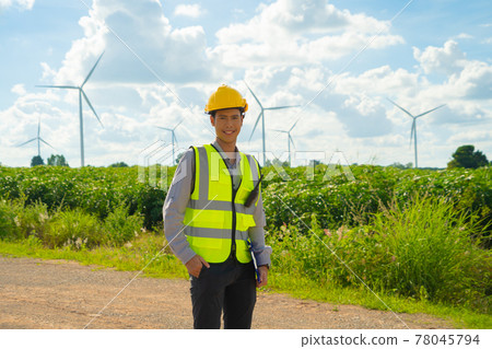 Portrait of Asian windmill engineer man, worker smiling, working on site at wind turbines field or farm, renewable clean energy source. Eco technology for electric power. industry environment. People 78045794