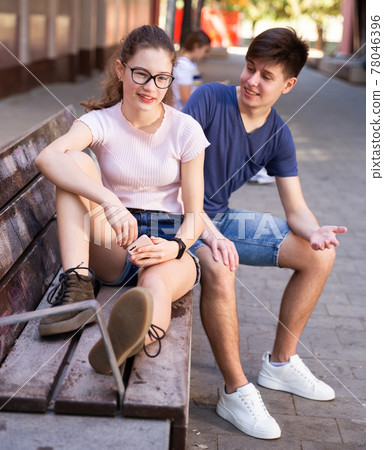 Teenager boy talking with girl on bench on summer day 78046396