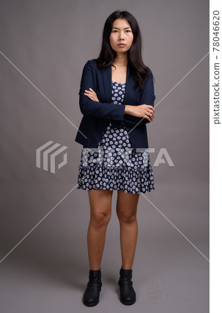 Asian woman wearing blue dress and cardigan sweater against gray Asian woman wearing blue dress and cardigan sweater against gray 78046620