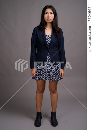 Asian woman wearing blue dress and cardigan sweater against gray 78046624