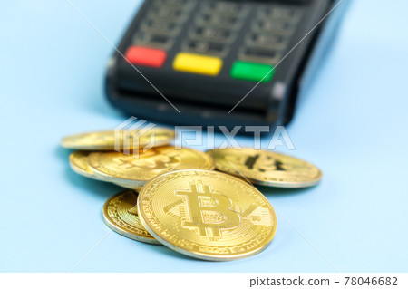 Bitcoin coins near POS payment terminal on the blue background. Crypto currency for payment Bitcoin coins near POS payment terminal on the blue background. Crypto currency for payment 78046682