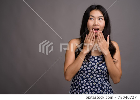 Asian woman wearing blue dress against gray background 78046727