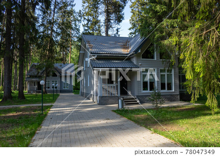 Two gray houses in a forest alley on a spring day Two gray houses in a forest alley on a spring day 78047349