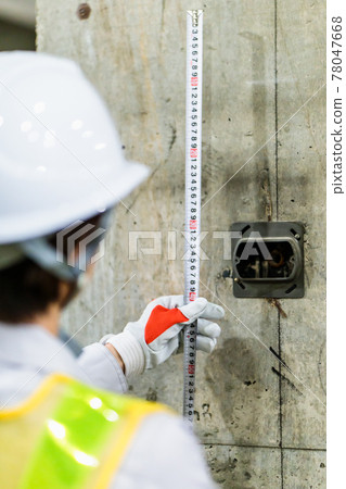 Female worker using a tape measure at a construction site Female worker using a tape measure at a construction site 78047668