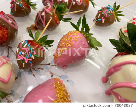 Beautiful bright colorful tasty sweet juicy fresh variety of strawberries in tampered white and dark milk Belgian chocolate with festive decoration and decor. A romantic dessert for a gift 78048087