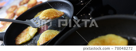 Potato latkes are cooked in skillet in kitchen closeup Potato latkes are cooked in skillet in kitchen closeup 78048272