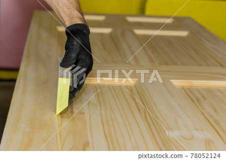 Worker hand in glove sanding with sanding block wooden door 78052124