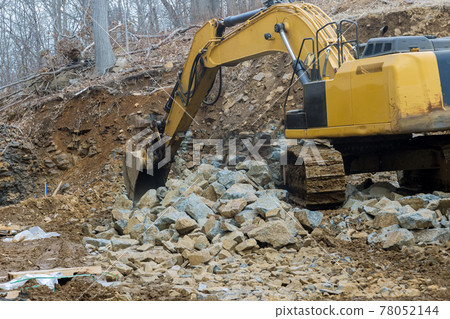 A large powerful loader overloads a pile of crawler excavator pours stones A large powerful loader overloads a pile of crawler excavator pours stones 78052144