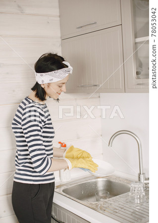 Woman in yellow gloves cleans her home Woman in yellow gloves cleans her home 78053042