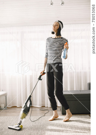 Woman vacuuming mat at home in a good mood Woman vacuuming mat at home in a good mood 78053068