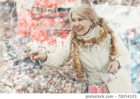 Adult woman is choosing Christmas decorations for house in the market 78054103