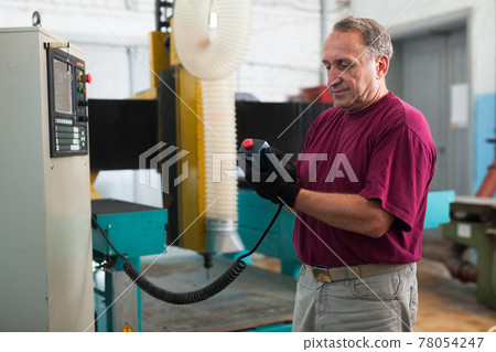 Elderly master manages CNC machine in factory Elderly master manages CNC machine in factory 78054247