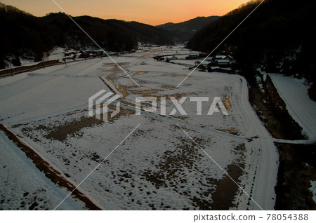 Sunset reflected in paddy fields in the middle of melting snow at dusk 78054388
