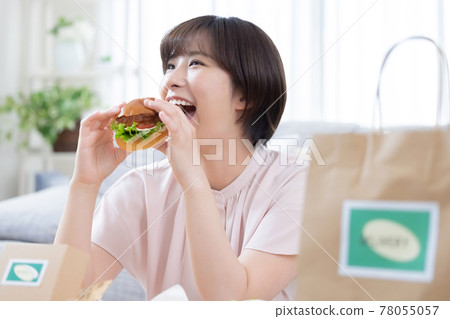 一位女士正在吃外賣訂購的食物 一位女士正在吃外賣訂購的食物 78055057