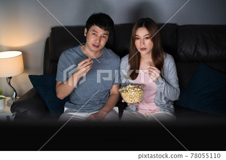 couple watching TV movie on sofa at night 78055110