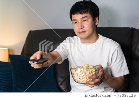 man watching TV on sofa at night man watching TV on sofa at night 78055129