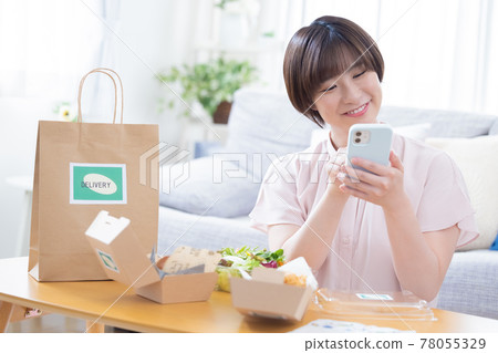A woman eating the food ordered by delivery A woman eating the food ordered by delivery 78055329