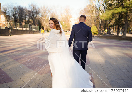 The groom holds the bride's hand and leads her. trust in the family. The groom holds the bride's hand and leads her. trust in the family. 78057413