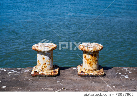 Two pillar bollards for mooring boats on a harbour wall Two pillar bollards for mooring boats on a harbour wall 78057905