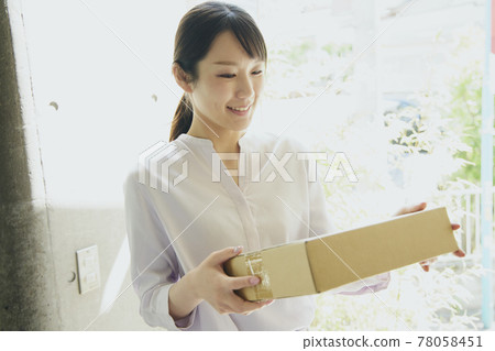 A woman receiving a package from a deliveryman 78058451