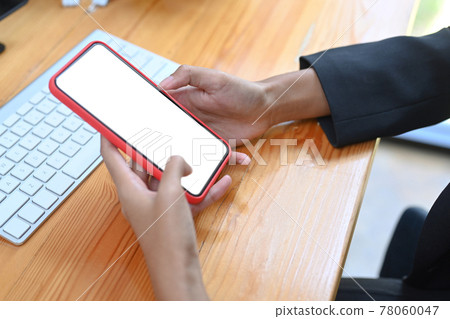 Mock up image of businesswoman holding smart phone with white screen on wooden desk. Mock up image of businesswoman holding smart phone with white screen on wooden desk. 78060047