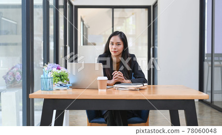Successful asian businesswoman sitting in front of computer laptop and smiling to camera. Successful asian businesswoman sitting in front of computer laptop and smiling to camera. 78060048