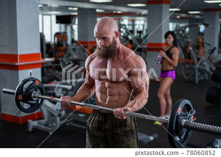Bald man with a beard in the gym. Muscular bodybuilder guy doing barbell exercises. Strong man with a naked torso. The young athlete is preparing for weightlifting competitions. Bald man with a beard in the gym. Muscular bodybuilder guy doing barbell exercises. Strong man with a naked torso. The young athlete is preparing for weightlifting competitions. 78060852