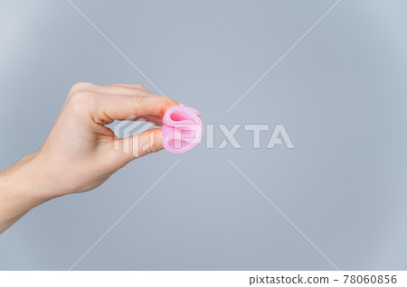 Woman holding folded menstrual cup on white background. Woman holding folded menstrual cup on white background. 78060856