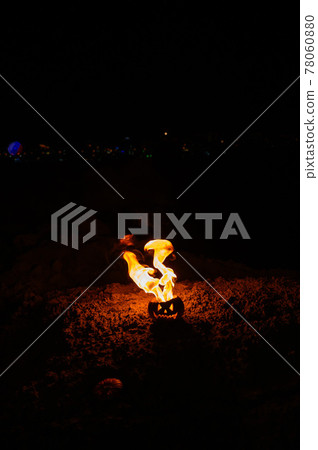 Tongues of flame in a pumpkin. jack-o-lantern on fire on a black background. Halloween symbol on the ground. Trick or treat. Close up. 78060880