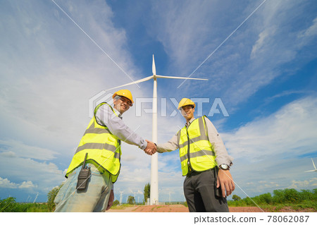 Teamwork of Asian windmill engineer group, worker working, shaking hands on site at wind turbines field or farm, renewable clean energy source. Eco technology for electric power. industry. People 78062087