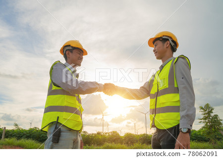 Teamwork of Asian windmill engineer group, worker working, shaking hands on site at wind turbines field or farm, renewable clean energy source. Eco technology for electric power. industry. People 78062091