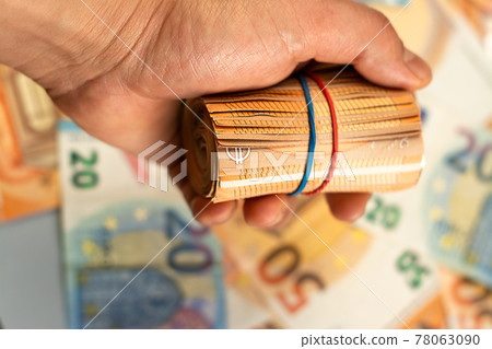 Close up of man hand holding roll of euro money bill on a money background, Euro money of European Union 78063090